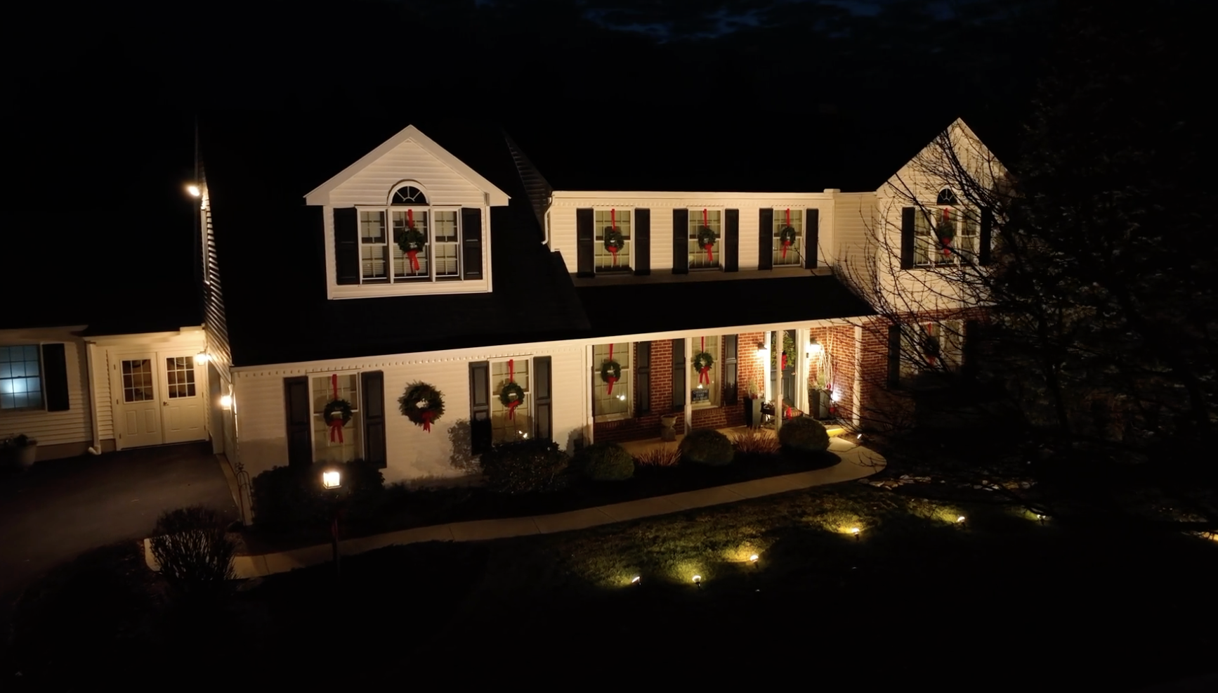 Colonial home with wreaths and elegant white lights