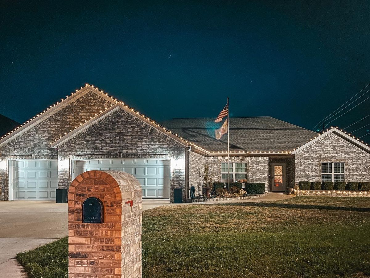 Brick ranch home with roofline lights at night